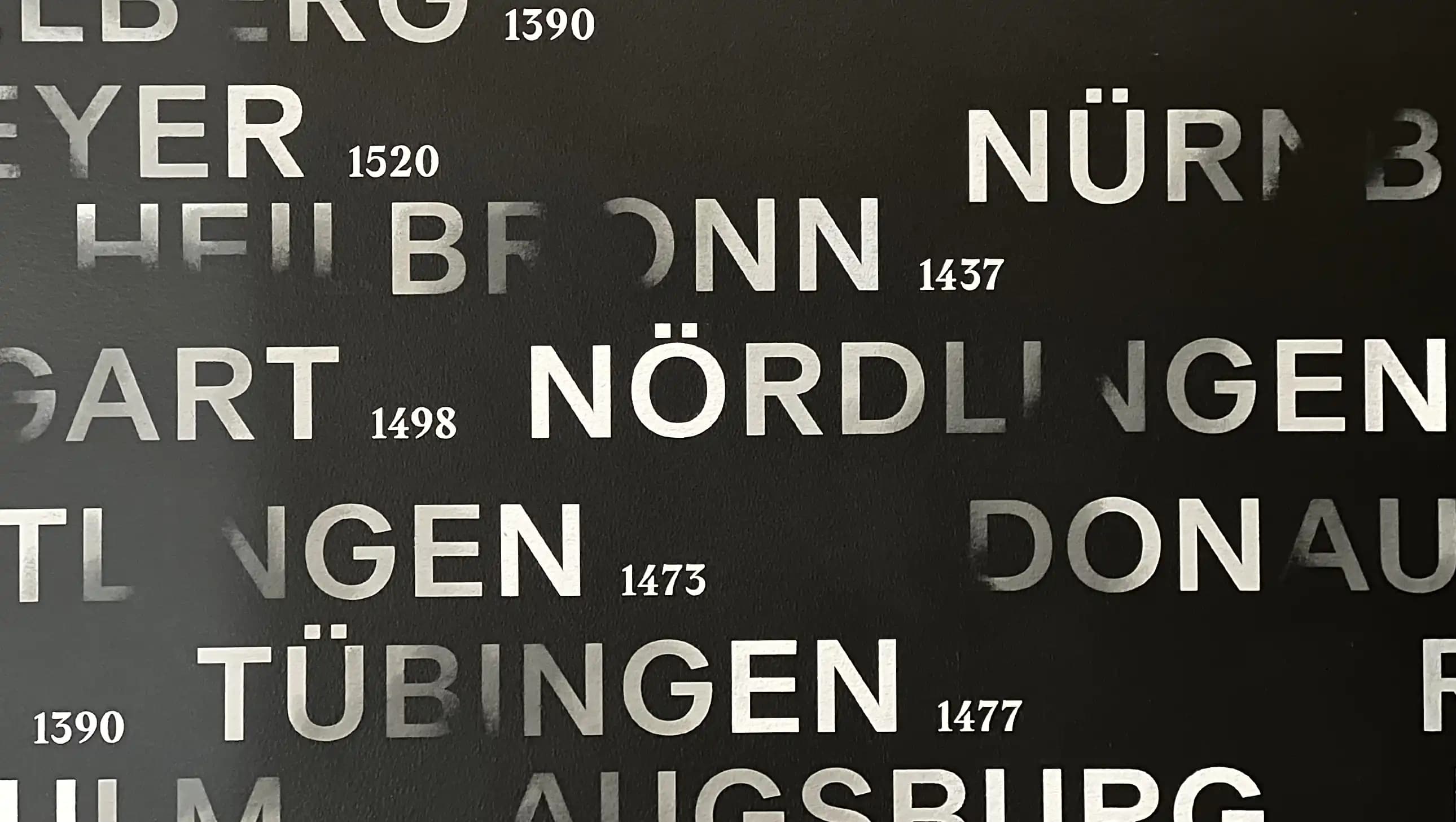 Buchstaben verschwinden fast im Schwarz, doch das Lesen holt sie zurück ins Licht.